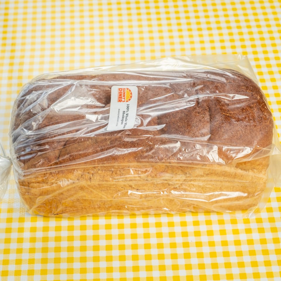 Packaged loaves of whole wheat bread labeled Sunny’s Diner on a yellow-and-white checkered tablecloth.