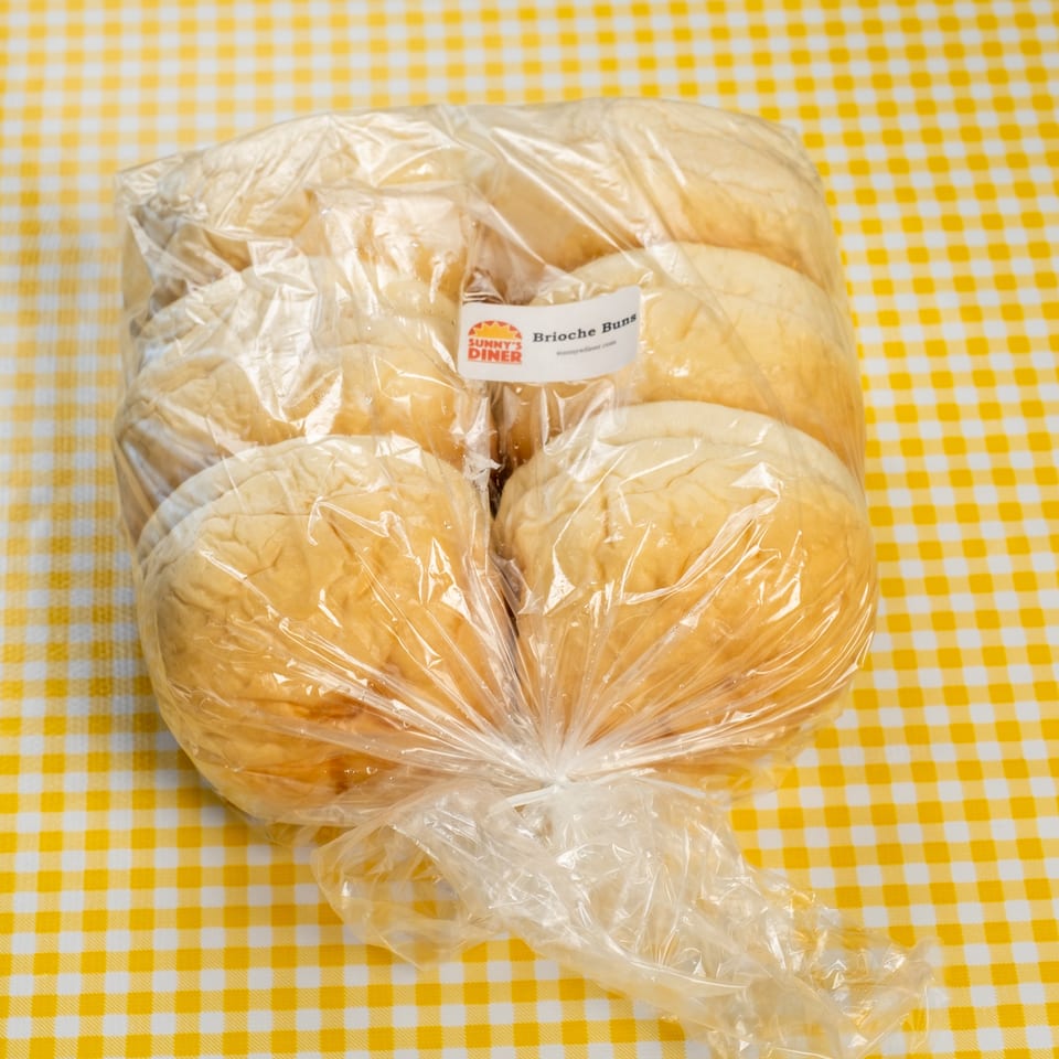 Bag of Sunny’s Diner brioche buns on a yellow-and-white checkered tablecloth.