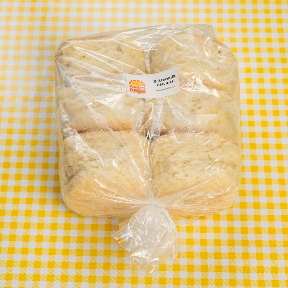 Bag of Sunny’s Diner buttermilk biscuits on a yellow-and-white checkered tablecloth.